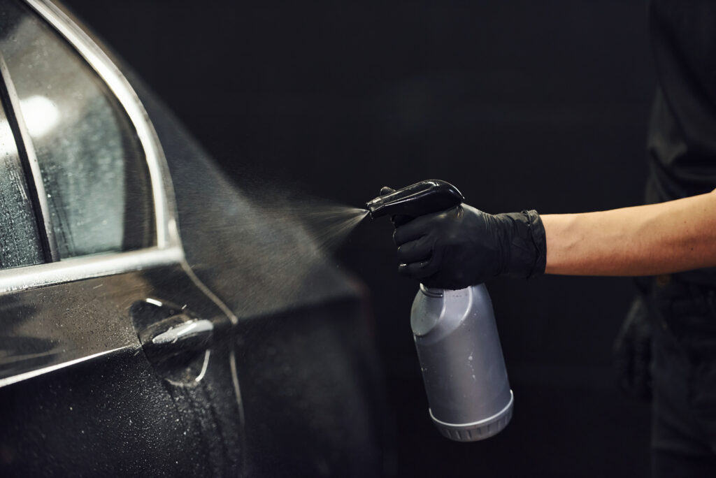 a person spraying a car door handle Cire céramique - scellant